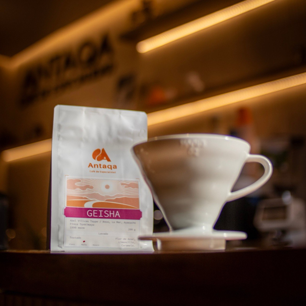 Bolsa de café Geisha de Antaqa junto a un gotero de porcelana en la barra