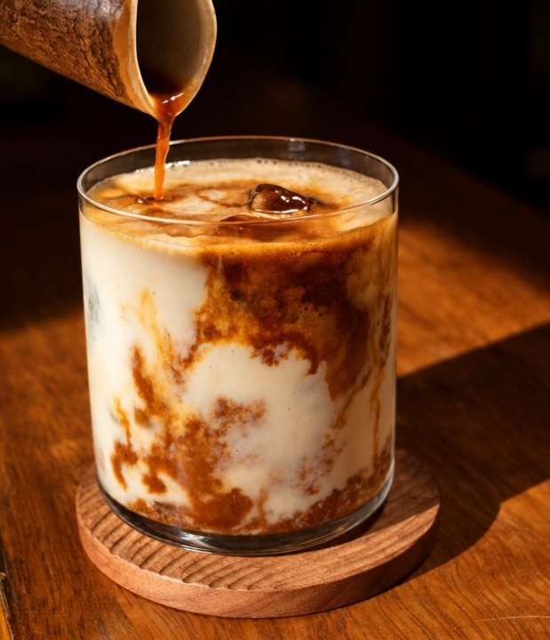 Café frío servido sobre leche en un vaso de vidrio